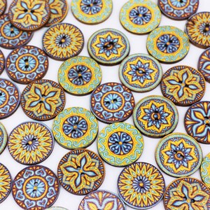 Könnte beinhalten: Sortiment runder Holzknöpfe mit komplizierten Mandala-Designs in Blau, Gelb und Braun.