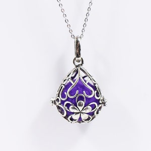 May include: A silver necklace with a purple charm that is shaped like a teardrop and has a delicate floral design.