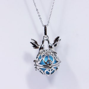 May include: Silver necklace with a blue glass peace sign charm inside a cage with two birds on top.
