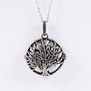 May include: A silver necklace with a round pendant featuring a detailed tree of life design.
