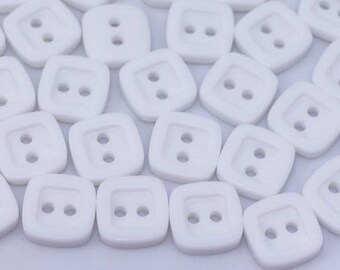 May include: A pile of white plastic buttons with two holes each. The buttons are square shaped with rounded corners.