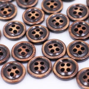 May include: A collection of brown wooden buttons with four holes each. The buttons are arranged in a random pattern on a white surface.