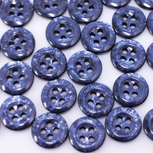 May include: A collection of blue plastic buttons with four holes each. The buttons have a speckled, marbled effect.