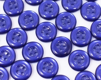 May include: A collection of blue plastic buttons with four holes each. The buttons are arranged in rows and are all the same size.