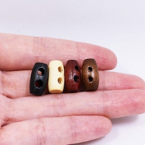 May include: Four wooden toggles with two holes each. The toggles are black, cream, brown, and reddish brown.