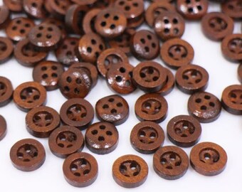 May include: A large pile of brown wooden buttons with four holes each. The buttons are scattered on a white surface.