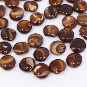 May include: A collection of brown and white swirl patterned round buttons. The buttons are made of a smooth, shiny material.