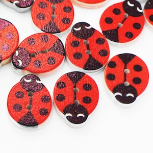 May include: A collection of red and black ladybug-shaped wooden buttons. The buttons have a glossy finish and are scattered on a white background.