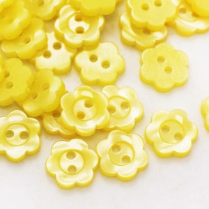 May include: A large pile of yellow plastic flower-shaped buttons.