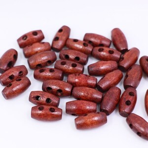 May include: A pile of brown wooden toggle buttons with two holes each. The buttons are oval shaped and have a smooth finish.