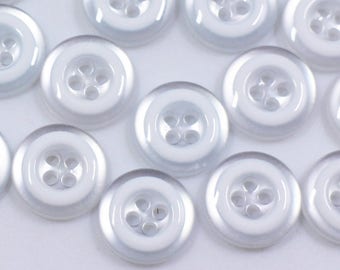 May include: A collection of white buttons with a silver iridescent sheen. The buttons have four holes and are arranged in a random pattern.