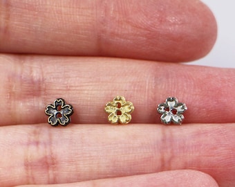 May include: Three small flower-shaped metal beads in black, gold, and silver.