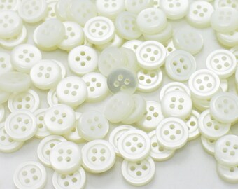 May include: A large pile of white plastic buttons with four holes each.