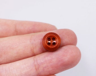 May include: A close-up of a brown wooden button with four holes.