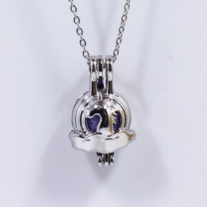 以下が含まれることがあります： 銀色のチェーンネックレスに、小さなハートが入った雲のような銀色のチャームが付いています。チャームは開いており、小さなものを収納することができます。