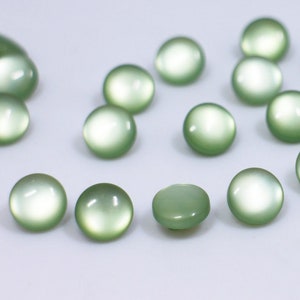 May include: A collection of pale green round buttons with a smooth, shiny finish.