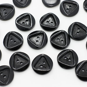 Peut inclure: Un ensemble de boutons noirs en forme de triangle avec deux trous chacun. Les boutons sont faits d'un matériau lisse et brillant.