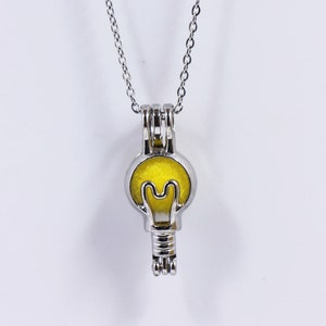 May include: A silver chain necklace with a lightbulb-shaped pendant. The pendant is open and has a yellow interior.