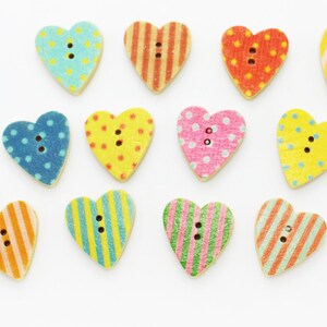 May include: Assortment of 12 heart-shaped wooden buttons with various colourful patterns, including polka dots, stripes, and floral designs.