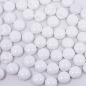 May include: A large group of white round buttons. The buttons are smooth and shiny.