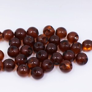 以下が含まれることがあります： 茶色のプラスチック製のトグルビーズのグループ。ビーズは丸く、中央に穴があります。クラフトやジュエリー作りによく使われます。