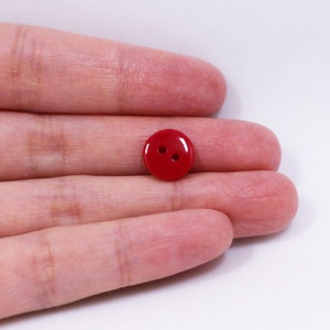 May include: A red plastic button with two holes.