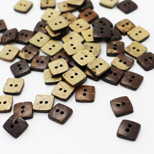 K&ouml;nnte beinhalten: Ein Haufen brauner und beigefarbener quadratischer Kokosnuss-Kn&ouml;pfe mit jeweils zwei L&ouml;chern.