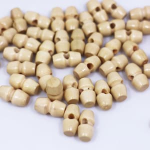 Könnte beinhalten: Nahaufnahme eines Stapels natürlicher Holz-Toggle-Knöpfe. Die Knöpfe sind hellbraun und haben eine glatte, abgerundete Form.