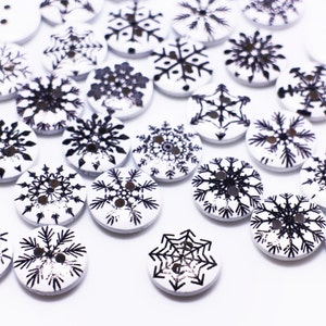 May include: A collection of white wooden buttons with black snowflake designs.
