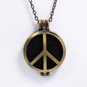 Op de afbeelding: Een gouden ketting met een vredesduif hanger. De hanger is rond en heeft een zwarte achtergrond met een gouden vredesduif.