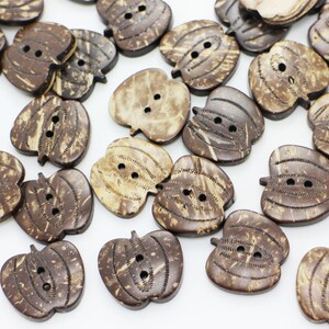 May include: A collection of brown coconut shell buttons shaped like pumpkins. Each button has two holes and a natural, rustic texture.
