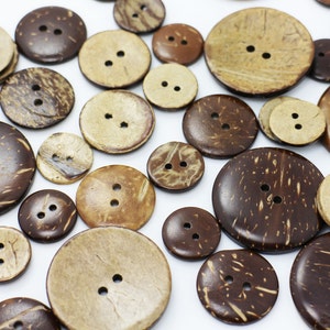 May include: Assortment of brown and beige coconut shell buttons with two holes each. The buttons are various sizes and have a natural, rustic look.