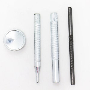 以下が含まれることがあります： 革に穴を開けるための銀色の革細工用ツールセット。セットには、丸いパンチ、ハンマー、アイレットを固定するためのツールが含まれています。