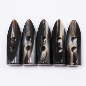 May include: Five black and white horn toggle buttons with two holes each.