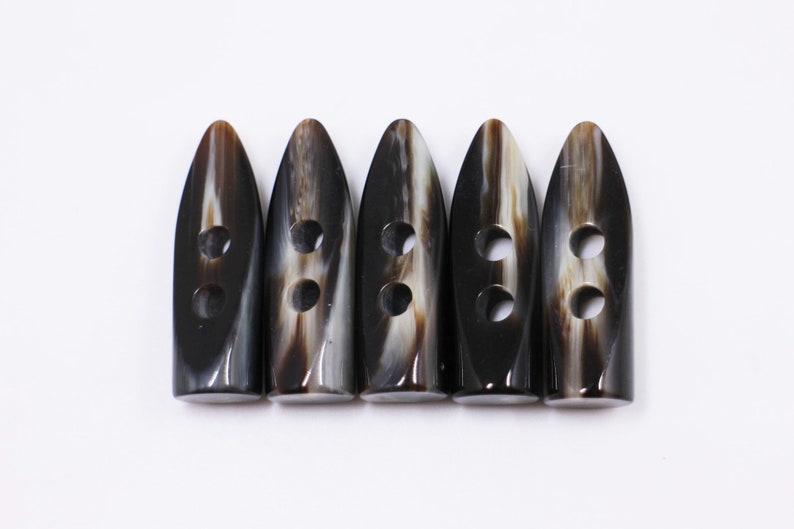 May include: Five black and white horn toggle buttons with two holes each.