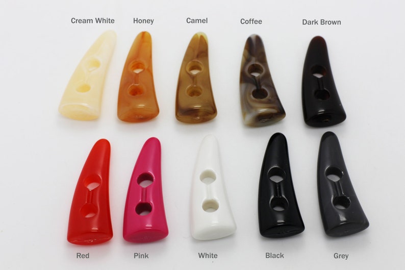 Peut inclure: Assortiment de 10 boutons en corne &agrave; deux trous dans diff&eacute;rentes couleurs, y compris blanc cr&egrave;me, miel, camel, caf&eacute;, brun fonc&eacute;, rouge, rose, blanc, noir et gris.