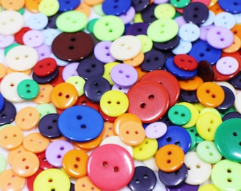 May include: A large assortment of colorful plastic buttons in various sizes and shapes. The buttons are in shades of red, orange, yellow, green, blue, purple, and brown.