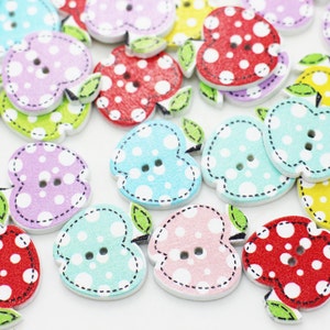 May include: Assortment of colorful wooden apple-shaped buttons with white polka dots. Each button has two holes for sewing.