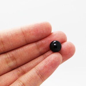 May include: A single black plastic button with a smooth, shiny surface.