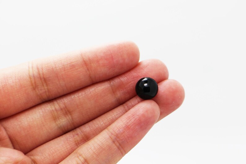 May include: A single black plastic button with a smooth, shiny surface.