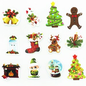 May include: Assortment of 12 Christmas-themed wooden buttons featuring various designs, including a Christmas tree, a stocking, a gingerbread man, a fireplace, a snow globe, and a reindeer. The buttons are decorated with colourful details and glitter.