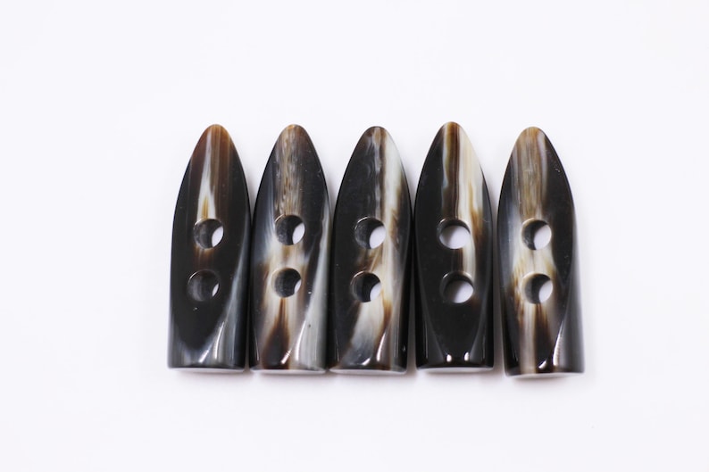 May include: Five black and white horn toggle buttons with two holes each.
