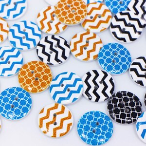 May include: Assortment of colourful wooden buttons with geometric patterns. The buttons feature zig-zag, grid and chevron designs in shades of blue, orange and black.
