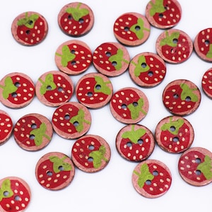 Peut inclure: Un ensemble de boutons en bois avec un motif de fraise. Les boutons sont peints dans des tons de rouge, vert et rose.