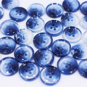 Könnte beinhalten: Eine Sammlung runder Knöpfe mit zwei Löchern und einem blauen und weißen Wirbelmuster.