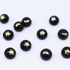 May include: A collection of black buttons with gold crescent moon and star designs.