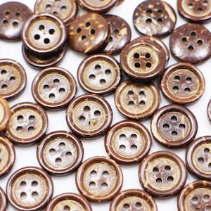 May include: A collection of brown coconut shell buttons with four holes each. The buttons are scattered on a white surface.