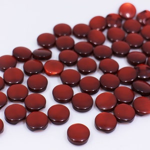 May include: A large group of red, round, flat buttons. The buttons are made of a shiny material and have a slight sheen.