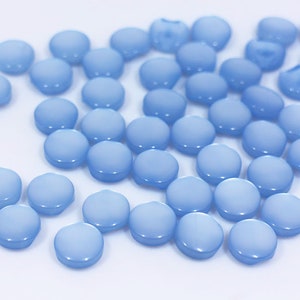 May include: A large group of light blue round buttons. The buttons are smooth and shiny.