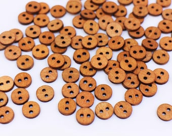 May include: A large group of brown wooden buttons with two holes each. The buttons are scattered on a white surface.